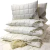 A stack of white, quilted pillows with a label on each. Produktbild-Vorschau