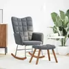 A grey rocking chair and ottoman are shown in a well-lit room with a large plant and a side table. Náhľad obrázku produktu