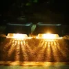 Two solar-powered outdoor lights illuminating a textured surface with warm yellow light. Produktbild-Vorschau