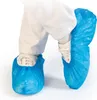 A close-up shot of a person's legs wearing white pants and white shoes covered by blue disposable shoe covers. Náhľad obrázku produktu