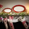 Christmas-themed mantelpiece with festive decorations, including plates, garlands, and stockings. Anteprima dell’immagine prodotto