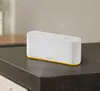A white smart home hub with a yellow accent sits on a dark countertop. Produktbild-Vorschau