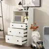 A white dresser with three drawers is shown in a room, with decorative items on top and beside it. Podgląd zdjęcia produktu