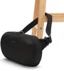 A black Pacsafe sling bag is hanging from a wooden stool. Anteprima dell’immagine prodotto