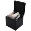 A black storage ottoman with its lid open, revealing some items inside.