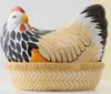 A ceramic chicken-shaped egg holder with a small chick peeking out from under its wing, sitting in a basket that says "FRESH EGGS". Náhled obrázku produktu