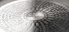 A close-up, detailed view of the textured bottom of a pot or pan, featuring a central logo and a patterned surface. Náhled obrázku produktu