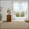 A rustic wooden column with a decorative sculpture on top, placed in a bright room with a window overlooking a field of flowers. Voir les images du produit