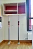 A shelf unit is being supported by two adjustable poles. Anteprima dell’immagine prodotto
