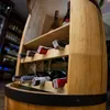 A wooden wine rack shaped like a barrel, with several wine bottles stored on its shelves. Náhľad obrázku produktu