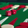 A close-up view of a backgammon board with red and cream checkers and two red dice. Produktbild-Vorschau