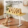 A standing desk with large 3D text indicating weight capacity, and a cat reaching for the desk. Produktbild-Vorschau