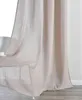 A close-up view of a light beige curtain hanging in front of a window. Produktbild-Vorschau