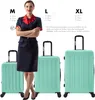 A woman in a uniform stands between three suitcases of different sizes (M, L, XL) to show scale. The suitcases are mint green. Produktbild-Vorschau