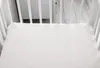 A close-up view of a white crib mattress with a fitted sheet. Produktbild-Vorschau
