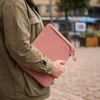 A person holding a pink laptop sleeve. Voir les images du produit