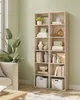 A living room setting with two light wood bookshelves filled with decorative items, a sofa, and a plant. Produktbild-Vorschau