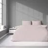 A neatly made bed with pink striped bedding in a room with a window casting shadows. Anteprima dell’immagine prodotto