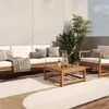 An outdoor patio set with a sofa, armchair, and coffee table on a rug, with plants and a wall in the background. Voir les images du produit