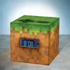A cube-shaped alarm clock designed to look like a Minecraft block, with a digital display showing the time. Náhľad obrázku produktu