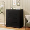 A black dresser with four drawers is shown in a room with a floor lamp and framed pictures on the wall. Náhled obrázku produktu