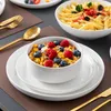 A table setting with a bowl of cereal and fruit, a bowl of pasta, and plates. Náhled obrázku produktu
