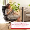 A woman is relaxing in a chair while a tower fan operates in the background. Produktbild-Vorschau