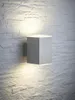 A modern LED wall light mounted on a textured stone wall. Produktbild-Vorschau