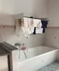A bathroom with a bathtub and a wall-mounted drying rack with clothes hanging on it. Produktbild-Vorschau