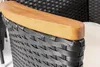 Close-up of the armrest of an outdoor chair, showing the woven rattan material and a wooden accent. Náhled obrázku produktu