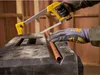 A person wearing gloves is cutting a copper pipe with a hacksaw on a black workbench. Voir les images du produit