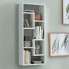 A white wall-mounted shelf unit with various items on display. Produktbild-Vorschau