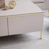 A close-up view of a modern coffee table with gold accents and legs, placed on a rug. Produktbild-Vorschau