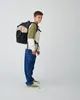 A young boy wearing a backpack stands against a plain white background. Anteprima dell’immagine prodotto