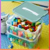A clear plastic storage container filled with colorful building blocks, with its lid open. Produktbild-Vorschau