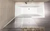 A top-down view of a bathtub with a glass shower screen partially open. Produktbild-Vorschau