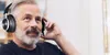 An older man wearing headphones and listening to something. Podgląd zdjęcia produktu