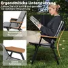 A woman is sitting on a camping chair outdoors, reading a magazine. Produktbild-Vorschau