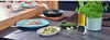 A kitchen scene with food preparation, including a steak, zucchini, garlic, and a potted herb. Produktbild-Vorschau