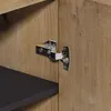 Close-up of a cabinet hinge attached to a wooden cabinet door, with a black shelf visible inside the cabinet. Anteprima dell’immagine prodotto