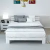 A white wooden bed frame with white bedding and gray pillows is shown in a bedroom setting. Náhled obrázku produktu