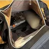 Schwarze Reisetasche mit Reißverschlussöffnung, Innenraum gefüllt mit einer Parfümflasche, einer Wasserflasche und einem Buch Anteprima dell’immagine prodotto