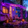 A camper decorated with purple LED string lights for Halloween, with pumpkins and chairs outside. Produktbild-Vorschau
