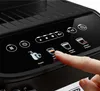 A close-up of a person's finger touching the control panel of a black coffee machine. Produktbild-Vorschau