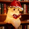 A cute ghost lamp wearing a Santa hat sits on a bookshelf and reads a book. Produktbild-Vorschau