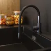 A modern kitchen sink with a black faucet and wooden bowls and jars of nuts on the counter. Podgląd zdjęcia produktu