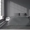 A bedroom scene with a bed dressed in grey striped satin bedding. Produktbild-Vorschau