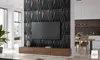A modern living room with a TV mounted on a textured black wall panel, with a wooden media console below. A dining area is visible in the background. Produktbild-Vorschau