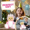 A young girl wearing a party hat smiles at the camera, with a large unicorn-themed teddy bear in front of her. A smaller teddy bear and a young boy are visible in a circular inset. Balloons and festive lights are in the background. Produktbild-Vorschau