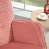 A close-up view of a pink corduroy armchair next to a small round table with a cup and saucer and a red decorative object. Náhled obrázku produktu
